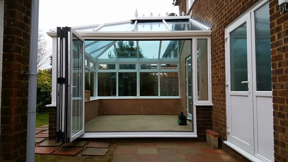 Conservatory interior with bi-fold doors open to the patio Everglaze Window Solutions Portsmouth